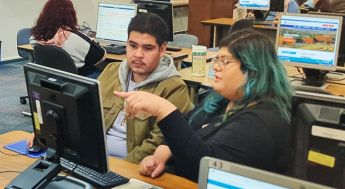 Student at a computer getting help enrolling in classes
