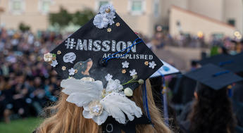 Student wearing a decorated graduation cap that reads Mission Accomplished
