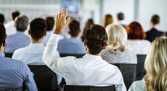 man raising hand in conference 