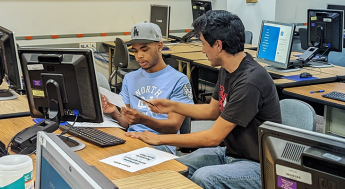 Student at a computer receiving help enrolling in classes from an LAMC representative
