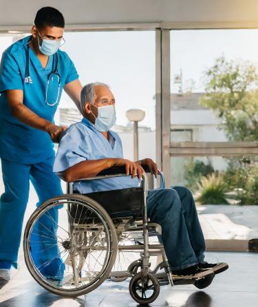 A healthcare worker pushing a patient in a wheel chair