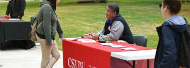 CSUN representative talking to a student in the quad as other students walk by