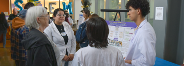 Biotech students presenting their research poster to an interested attendee