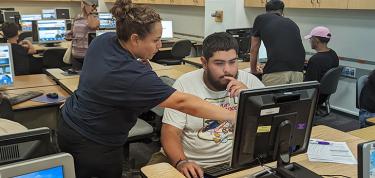 LAMC representative helping a student on a computer enroll in classes