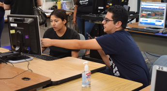 Student at a computer receiving help enrolling in classes